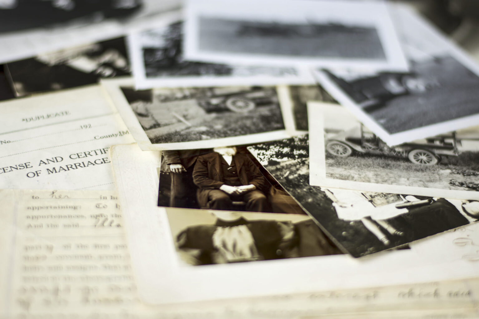 A collection of black and white photographs and documents scattered on a table.