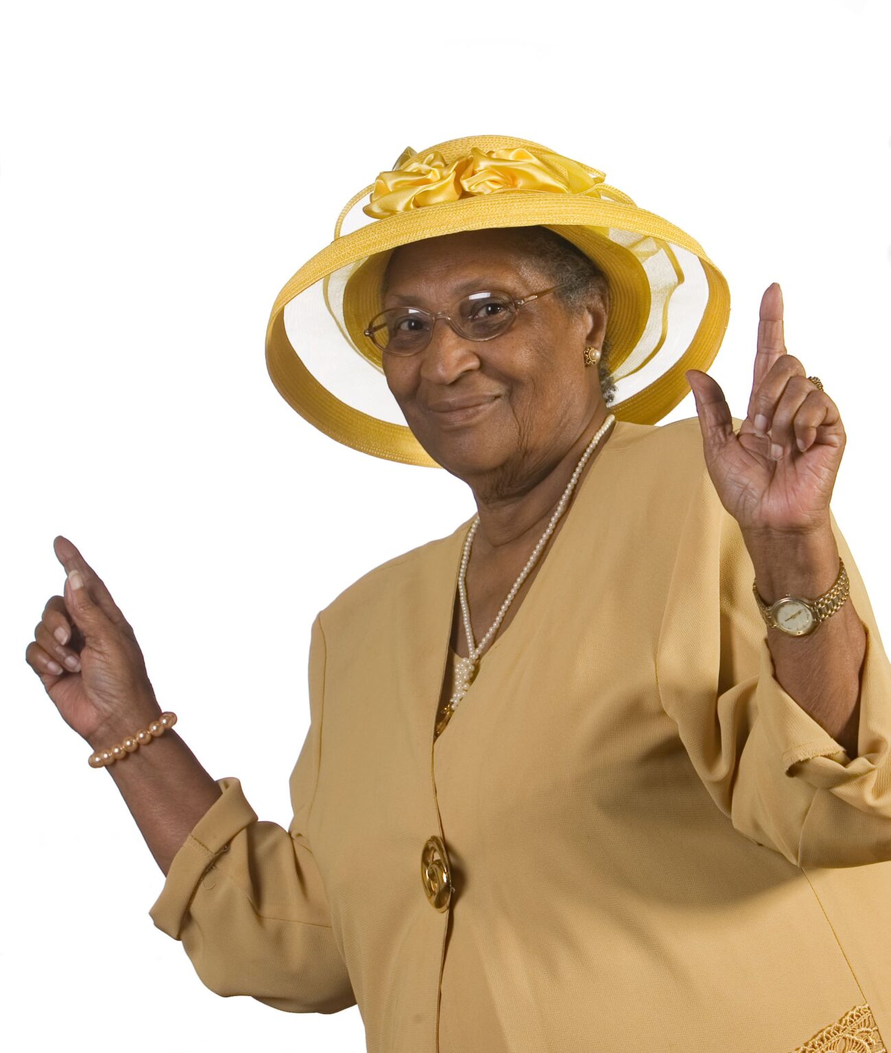 A photo of a woman wearing a yellow hat and dress, with their hands up in a dancing pose.